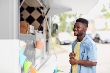 Poster - street sale and people concept - happy smiling male customer looking at billboard at food truck