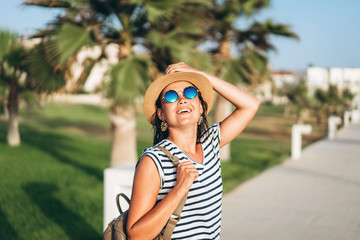 Wall Mural - Pretty pan asian tourist girl in hat and sunglasses walking outdoor.