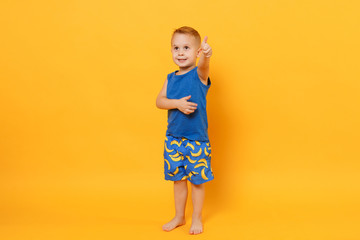 Wall Mural - Smiling fun kid boy 3-4 years old wearing blue beach summer clothes isolated on bright yellow orange wall background, children studio portrait. People, childhood lifestyle concept. Mock up copy space.