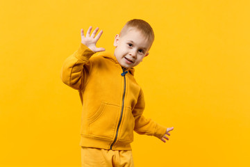 Wall Mural - Little cute kid boy 3-4 years old wearing yellow clothes isolated on bright orange wall background, children studio portrait. People sincere emotions, childhood lifestyle concept. Mock up copy space.