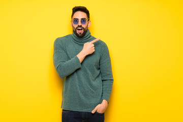 Wall Mural - Handsome man with sunglasses pointing to the side to present a product