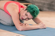 © zinkevych - Green-haired woman wearing sport clothes stretching after fitness