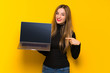 © luismolinero - Young pretty woman over yellow background showing a laptop