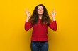© luismolinero - Teenager girl with red sweater over yellow wall in zen pose