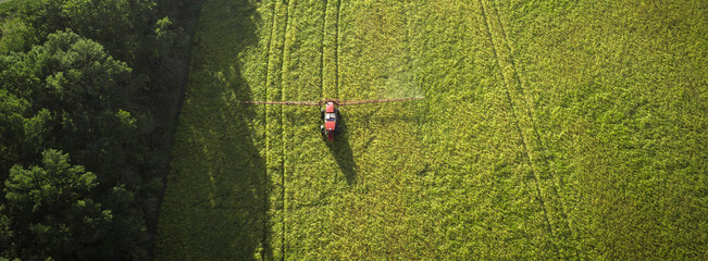 Agricultural machinery in the field. Tractor with a sprayer. Aerial view