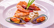 Fine dining mixed seafood set on the white plate, Shrimps, squids, green mussels
