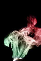 Splash glicerine on vape spiral. Two colour green and red clouds of fog with visible tracers. Vape culture and no smoking.