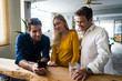 © Westend61 - Smiling business team looking at cell phone together in loft office