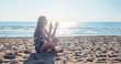 Smiling girl meditates on the beach