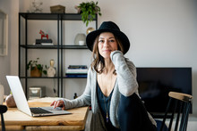 Portrait Of Smiling Woman Wearing Hat Using Laptop At Home