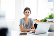 © Westend61 - Happy woman sitting at desk, working from home, using laptop
