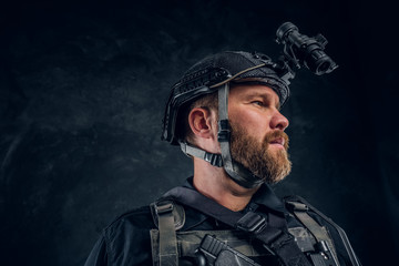 Wall Mural - Portrait of a special forces soldier wearing body armor and helmet with a night vision. Studio photo against a dark textured wall