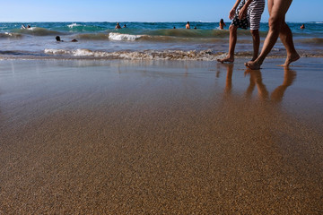 Legs of two young men walking a long the beach