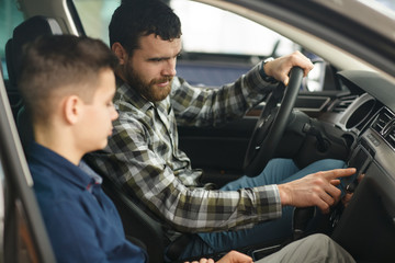 Wall Mural - Handsome mature man and his young son buying a new automobile together