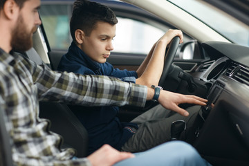 Wall Mural - Handsome mature man and his young son buying a new automobile together