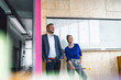 © Westend61 - Mature man and his assistant with scooter, standing in office in front of white board