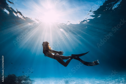 Dekoracja na wymiar  kobieta-freediverka-z-pletwami-plywajaca-nad-piaszczystym-morzem-i-promieniami-slonecznymi-pod-woda