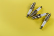 A set of new spark plugs a yellow background.