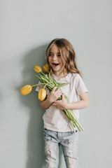 Wall Mural - little beautiful girl with yellow tulips