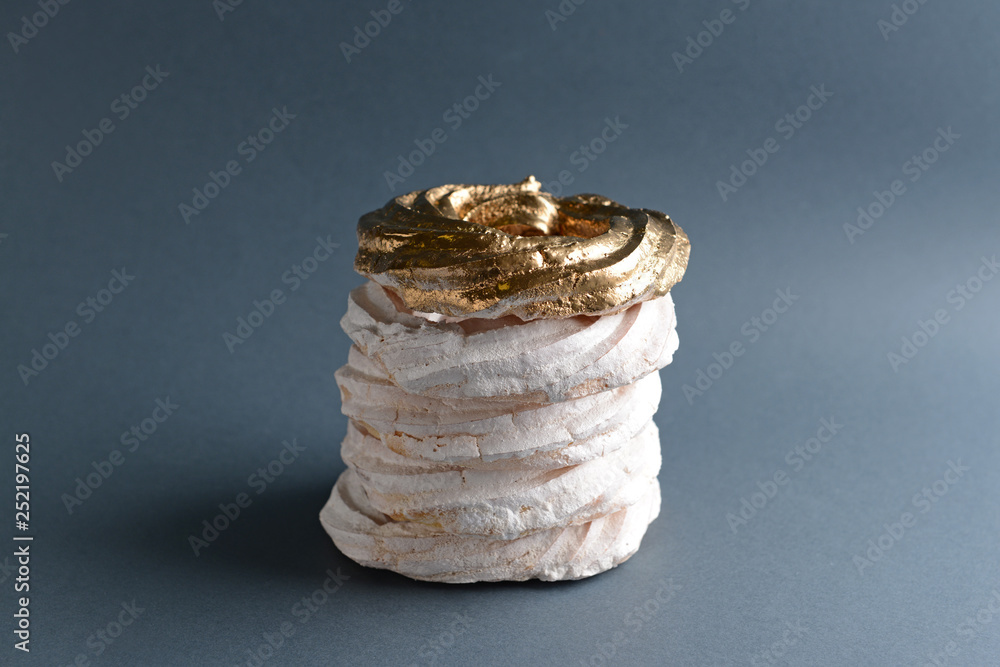 Golden meringue among white ones on grey background. Concept of uniqueness