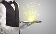 © ra2 studio - Elegant young waiter serving mysterious light on tray