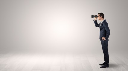 Wall Mural - businessman looking forward with binoculars in an empty space