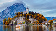 Panoramic scenic sunset over Austrian alps lake. Boats, yachts in the sunlight infront of church on the rock with clouds over Traunstein mountain at the alps lake near Hallstatt Salzkammergut Austria