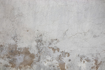 Gray wall ruined by time, bad weather and humidity. Cracks, mold, peeling paint and plaster. Texture, material background.