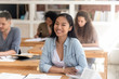 © fizkes - Smiling smart asian student looking at camera sitting at desk