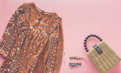 Girls' fashion background, brown dress, trendy straw bag and bracelets on pastel pink, flat lay, top view, sopy space, selective focus