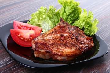 grilled pork chops with tomato, leaves lettuce and ketchup on plate.