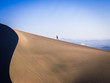 man walking up sand dunes in the desert