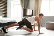 © estradaanton - Young well-built man go in for sports in apartment. He stand on hands and move legs. Guy look straight forward. He exercise alone in room.