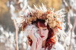 Portrait of a beautiful girl in a white vintage dress and autumn wreath of dried flowers on the head in the midst of airy and fluffy plants. Mysterious fluffy seeds of a Milkweed (Silkweed).