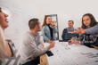 © qunica.com - A group of young entrepreneurs discussing their next project at a meeting pointing at the blueprint which is at the middle of the table.