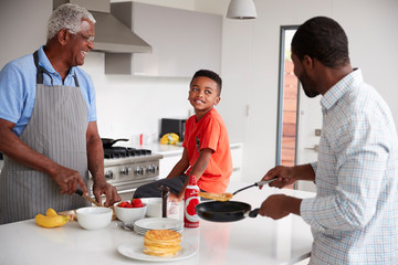 Wall Mural - Multi Generation Male Family In Kitchen At Home Making Pancakes Together