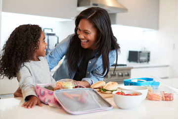 Daughter In Kitchen At Home Helping Mother To Make Healthy Packed Lunch