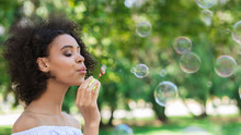 Portrait of young beautiful woman making soap bubbles