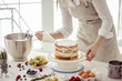 © alfa27 - awesome confectioner squeezing cream on cake at kitchen.close up cropped photo