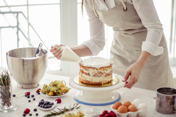 awesome confectioner squeezing cream on cake at kitchen.close up cropped photo