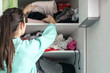teen girl takes her things from the top shelf of the cabinet