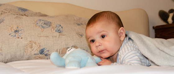 cute 4 months old baby boy having tummy time and making funny faces