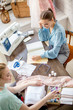 © alfa27 - two young elegant seamstress collaborate on choosing design and fabric for a new clothing collection at the desk in the dressmaker s studio