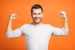 © denis_vermenko - Happy winner. Happy young handsome man gesturing and keeping mouth open while standing against orange background.