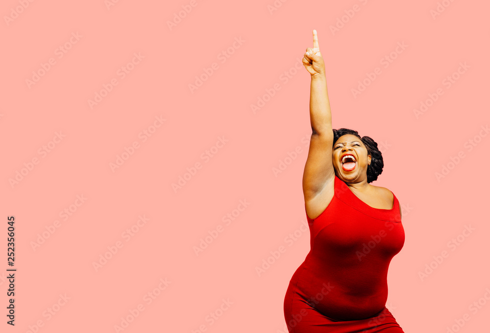 Horizontal portrait of a very happy and excited woman celebrating success with arm up, mouth open and finger pointing up	 - obrazy, fototapety, plakaty 