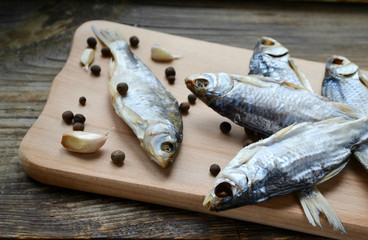 Salty stockfish cod on wooden board with gaarlic and pepper