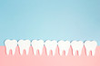 White paper teeth on pink and blue background. Dental health concept. Flat lay, top view, copy space for text.