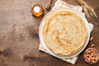 Crepes, thin pancakes with honey and nuts on a white plate . Wooden background .