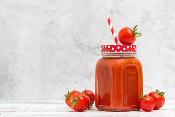 Wall Mural - Fresh tomato juice in jar and cherry tomatoes on light background. With copy space