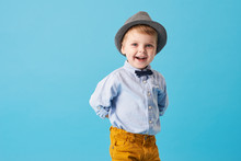 Portrait Of Happy Joyful  Little Boy Isolated On Blue Background. Toddler Child In Hat And Fashionable Suit Smiling And Have A Fun 